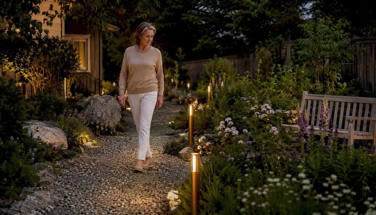 Path Lighting Explained: Safe, Stylish Walkways for Homeowners Woman walking on softly lit garden walkway at dusk