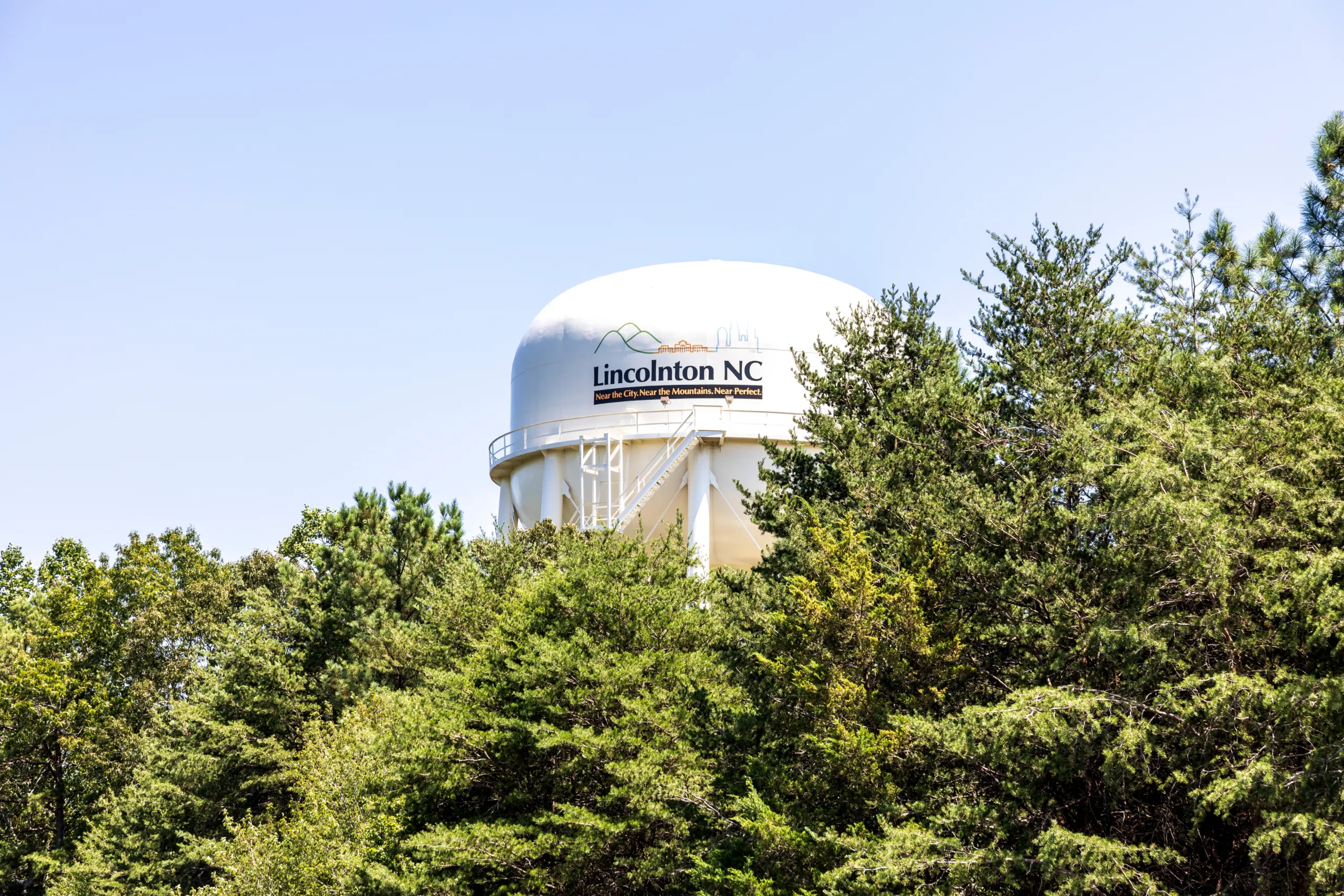 LiNCONTON, NC, USA-9 AUGUST 2019:The city water storage tank, framed by evergreens and the blue sky.