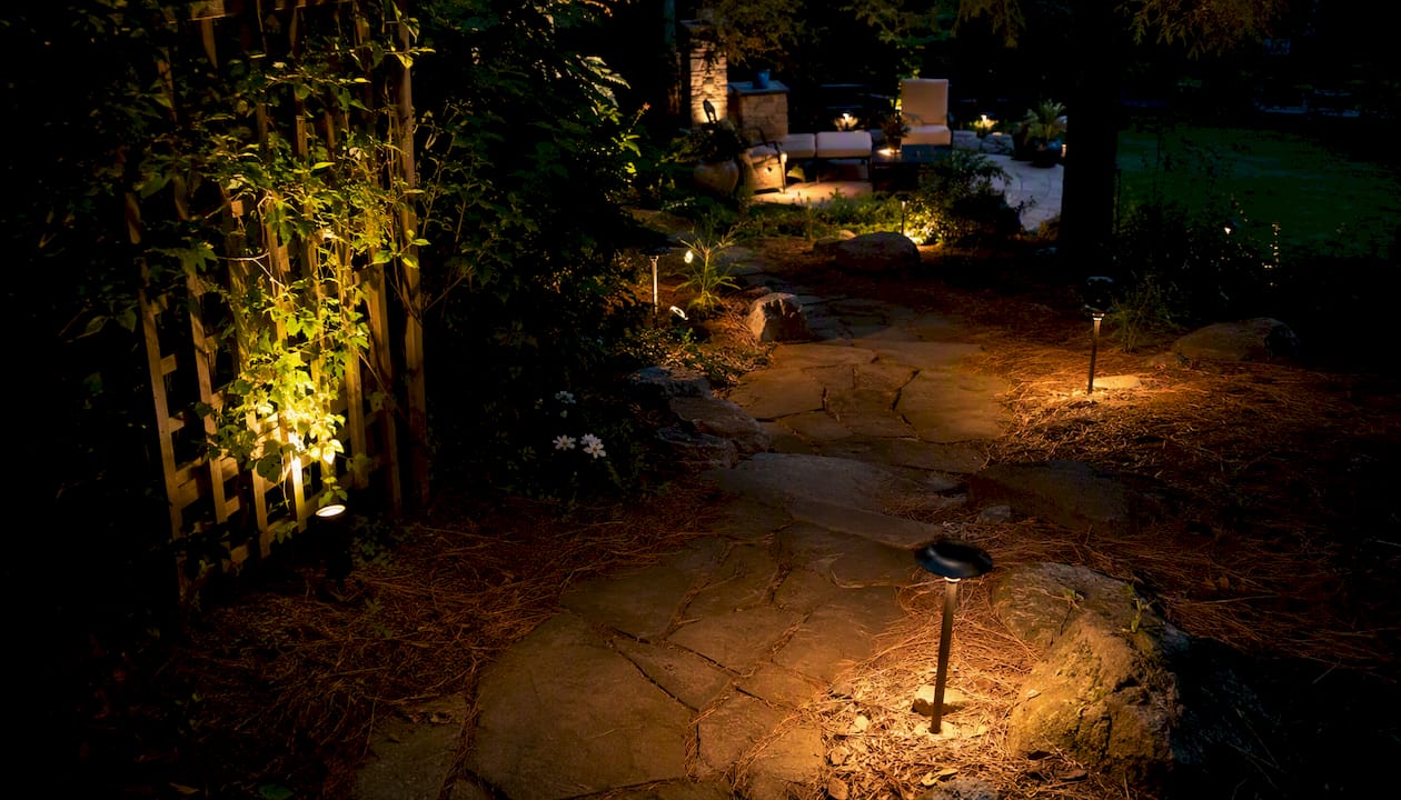 Landscape Lighting Brightness Levels: A Homeowner's Guide Layered outdoor lighting on garden tree, path, and patio