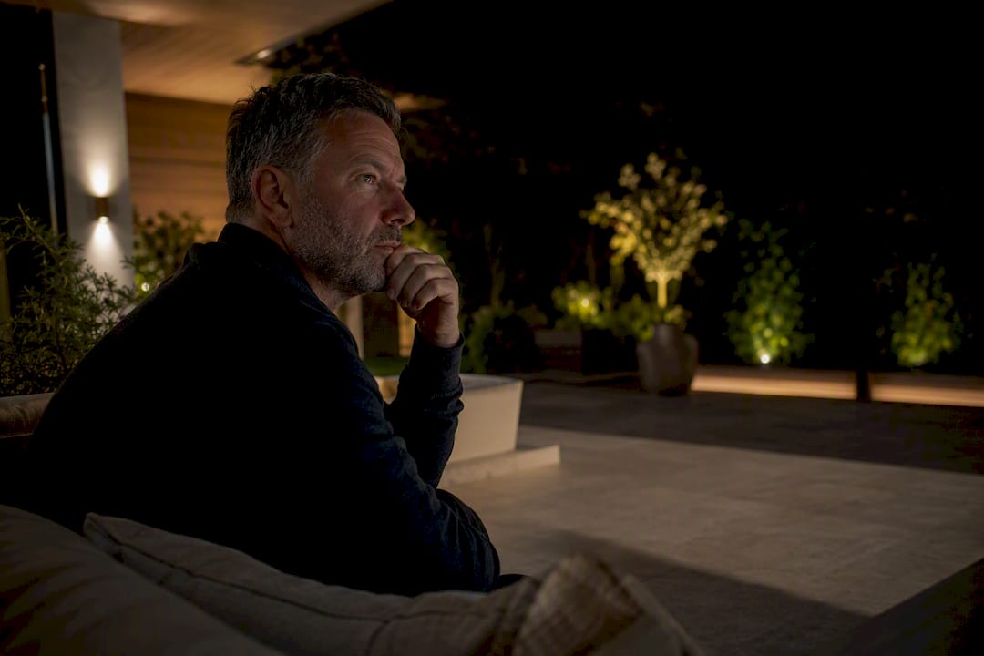 How Outdoor Lighting Reduces Glare Without Losing Curb Appeal Person assessing outdoor light glare from patio