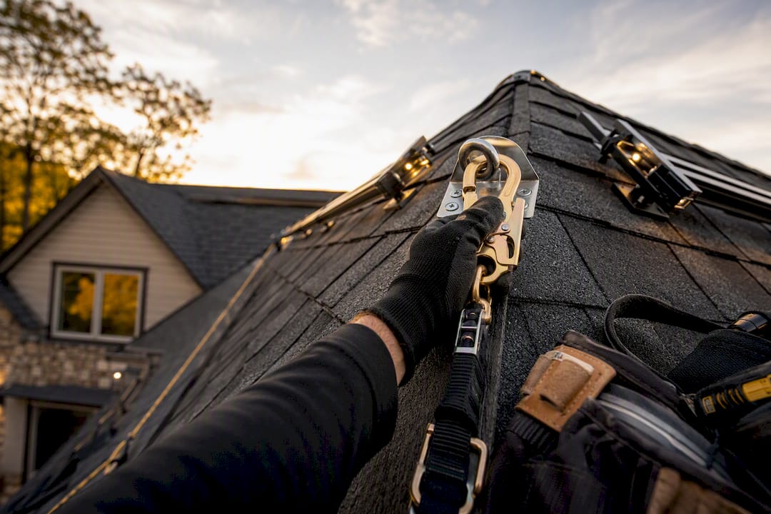 What Permanent Christmas Lights Cost in 2026 Installer securing safety gear on steep roof