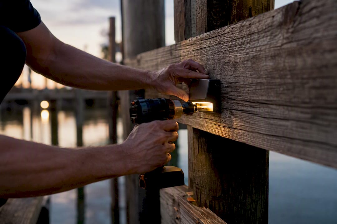 Technician installing dock lighting mounting bracket close-up
